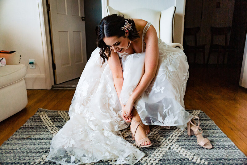 Bride sitting and leaning to put her shoe on