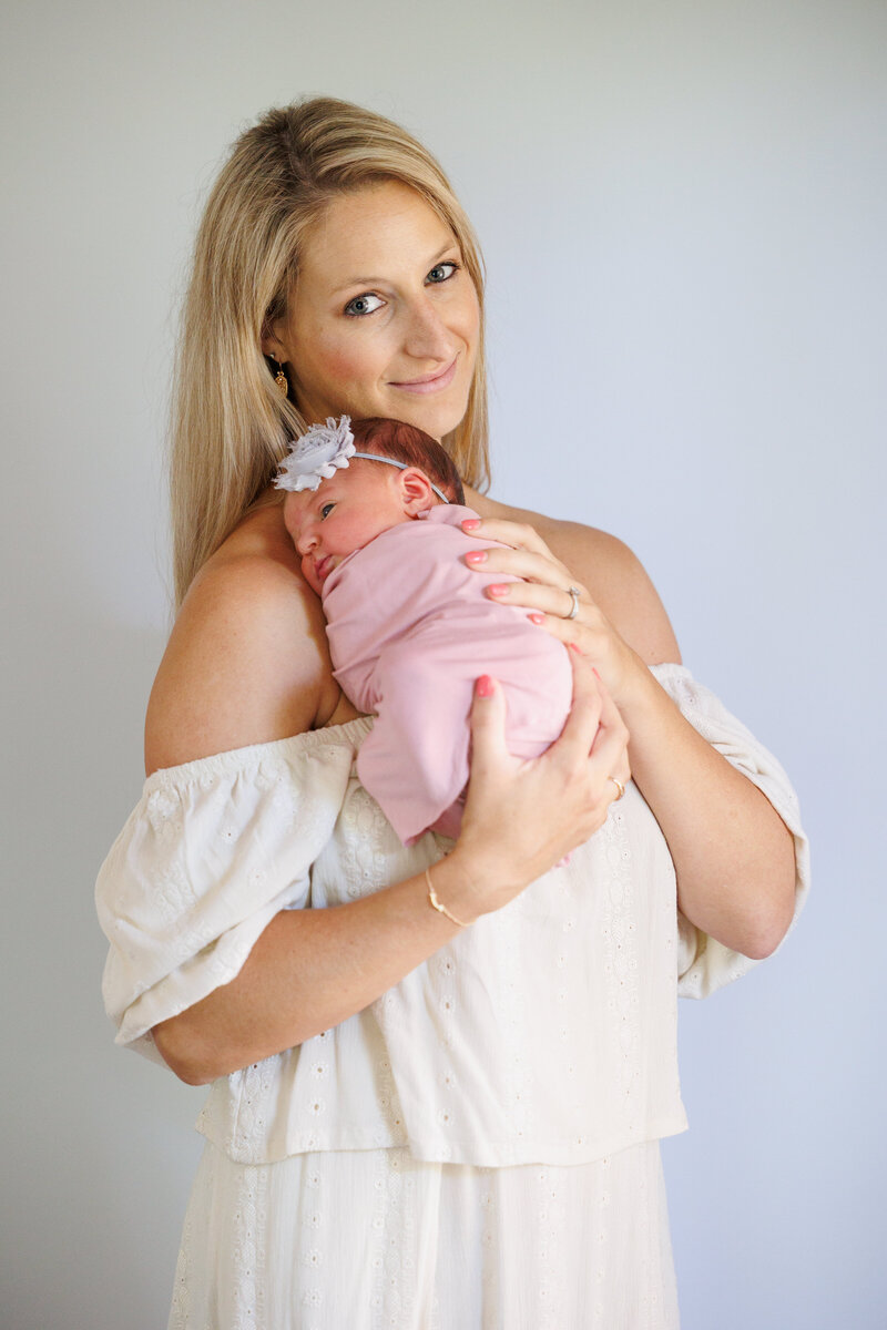 I mother homding a newborn baby girl wearing pink