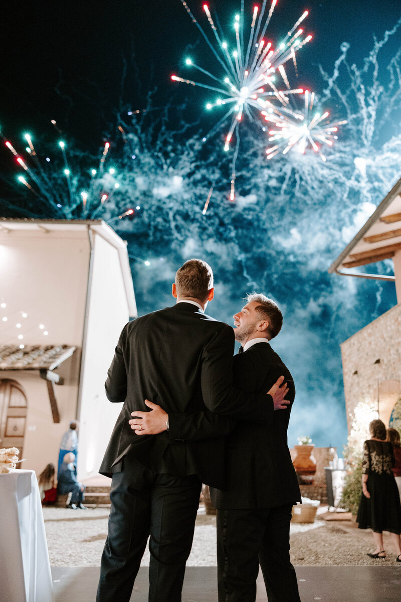 Photo of grooms admiring firework show at their wedding taken by Maine wedding photography