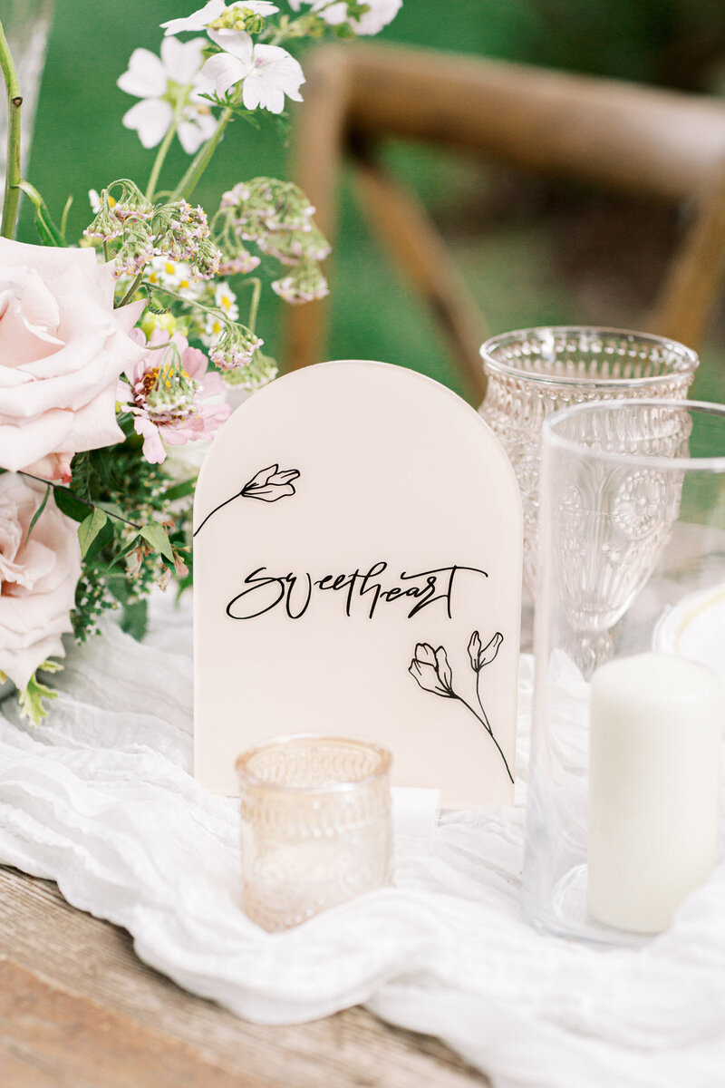 Close up of a wedding table number sign next to candles, representing customized calligraphy offerings for wedding and events. 