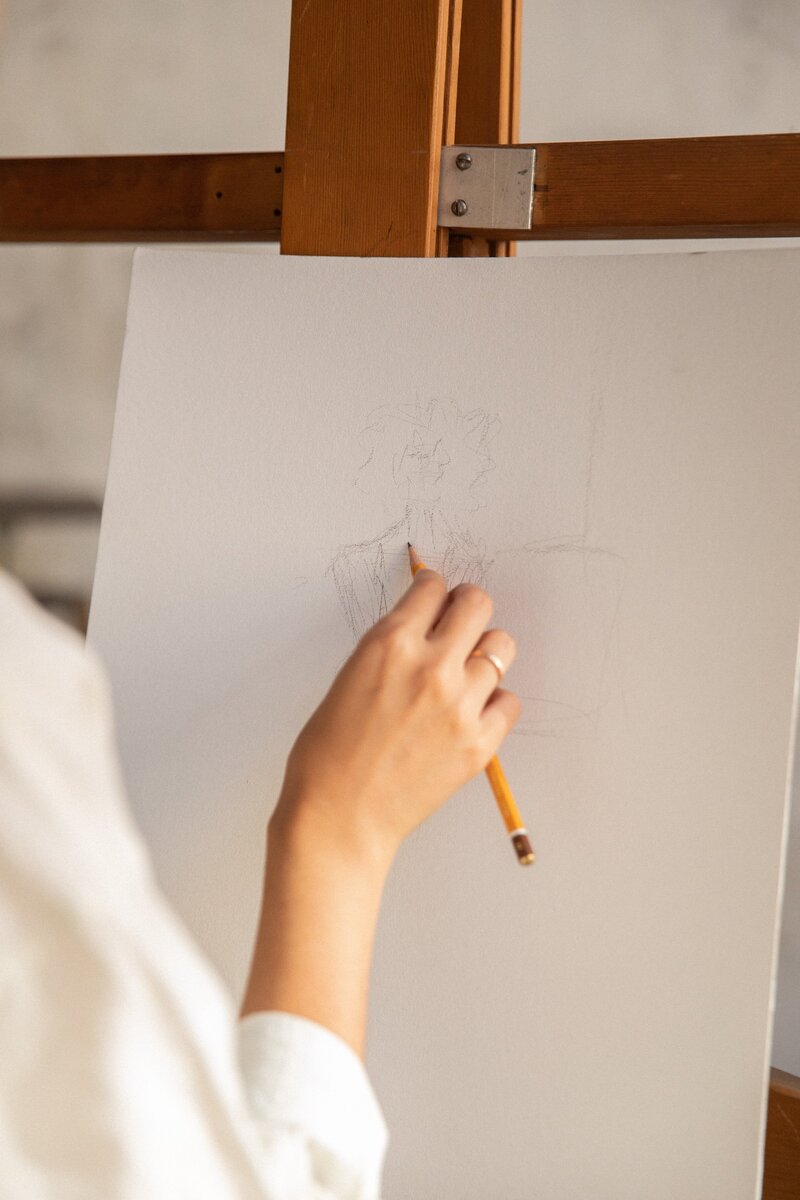 A woman drawing with a pencil on an easel.