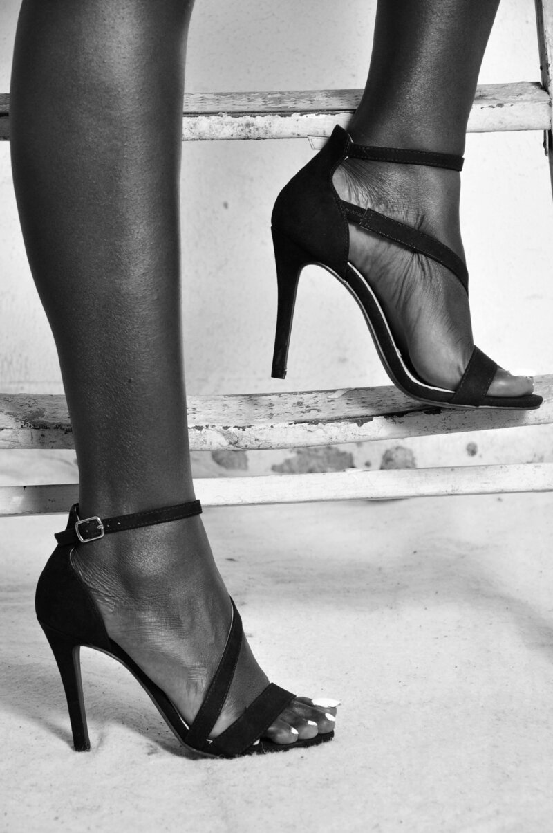 Black and white photo of legs wearing tall black heels