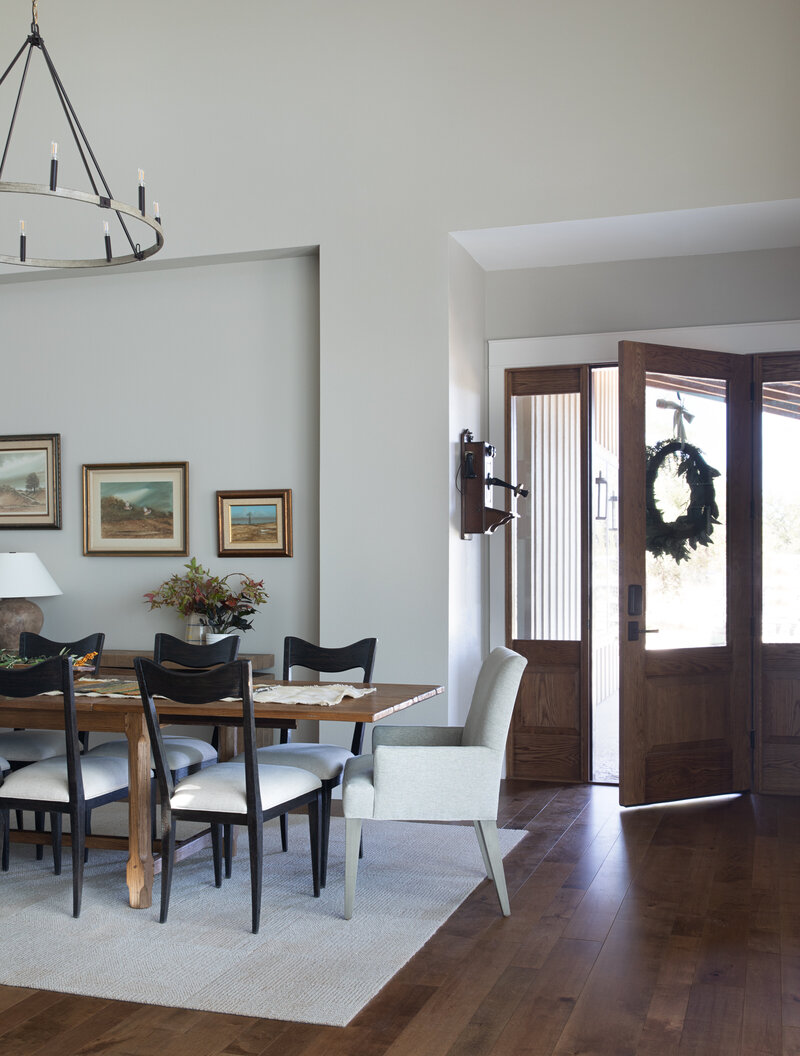 A dark heavy exterior door is partially open to the entryway with a dining table and chairs