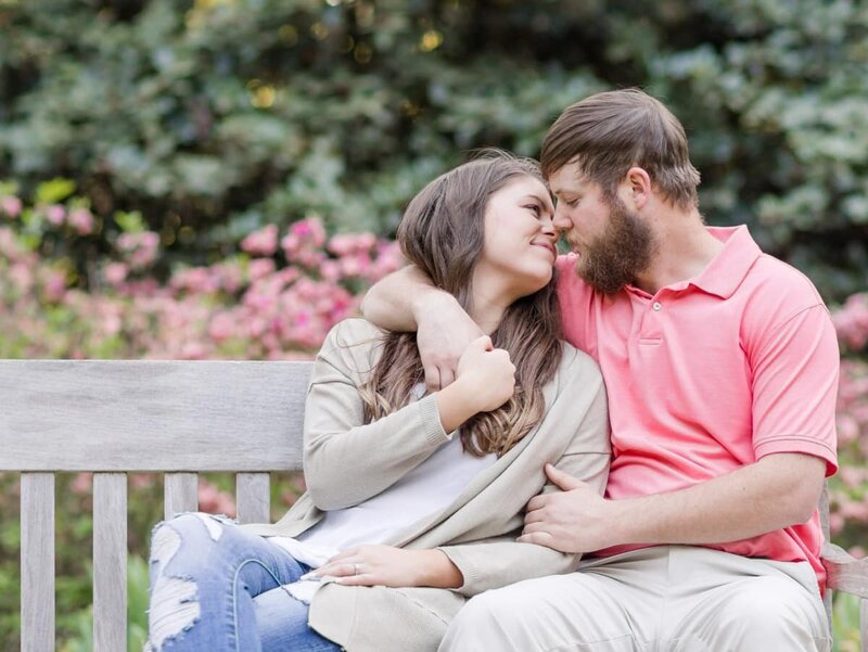 Engagement photo o f a couple sitting together with his arm around her about to share a  kiss