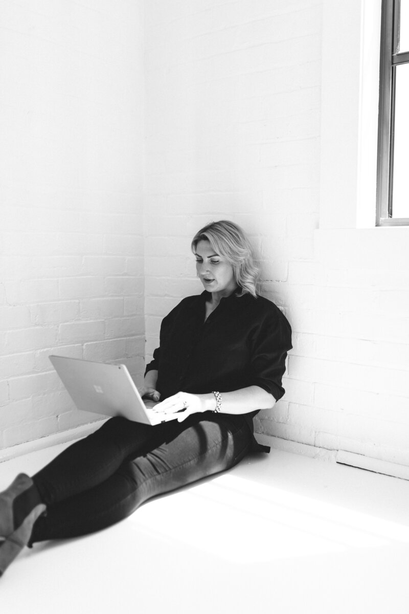 Lady sitting on ground with laptop on  lap