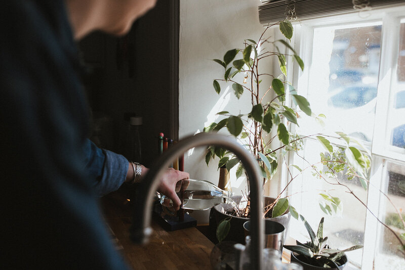 Business coach waters her plants in her kitchen in Oxfordshire