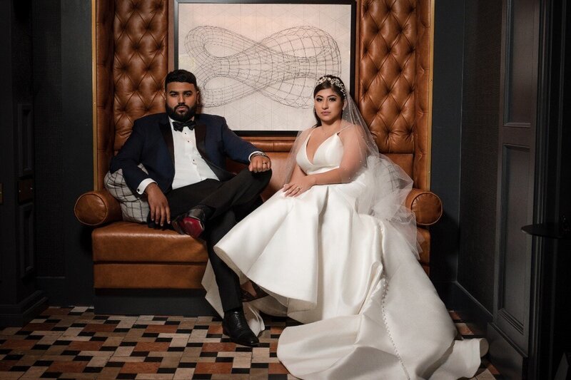 Bride and groom seated in a regal, fashion-forward portrait at The Union Club Hotel at Purdue University.