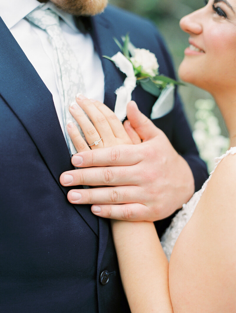 bride and groom holding hands on groom's chest