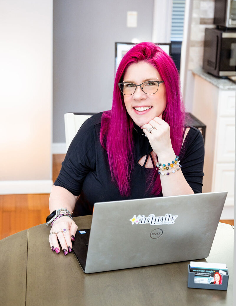 Barb Pritchard sits at her laptop smiling at the camera.