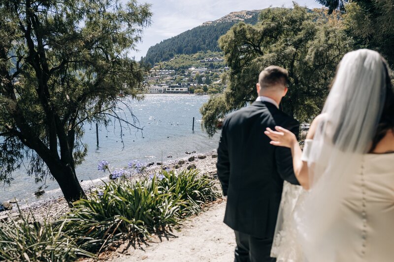 lake wakatipu in queenstown seen through some trees and past a blurry wedding couple