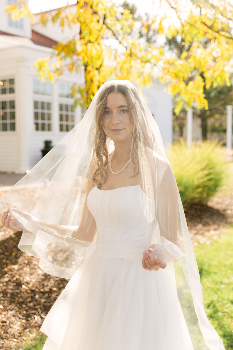 Bride standing in sunlight with long veil during bridal portraits — Colorado wedding photography at The Manor House