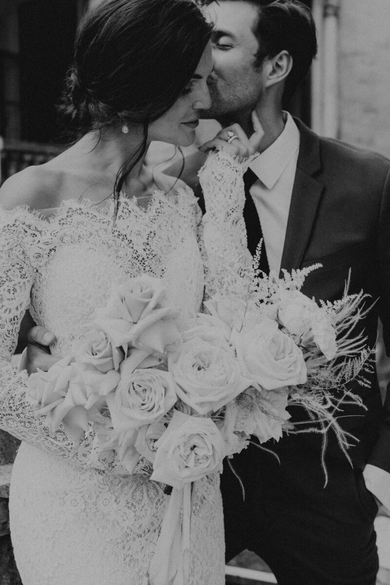 Black and white moody portrait of wedding couple with floral bouquet.