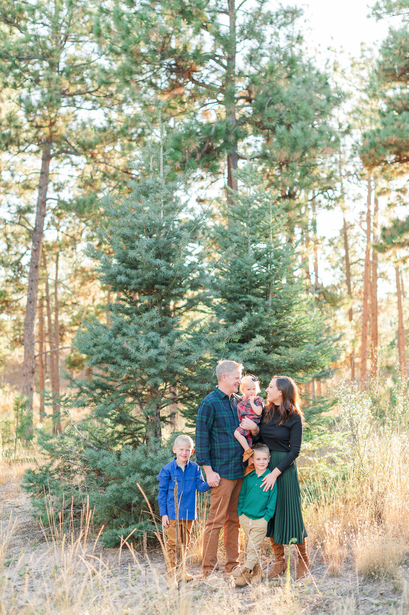 A family poses by evergreen trees in Black Forest Regional park during sunset.