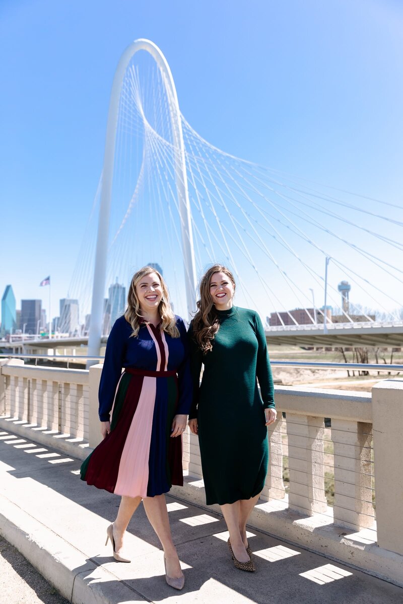 Brianna Castillo and Keelie Luttrell of Haven Realty Group standing in front of the Dallas skyline and Margaret Hunt Hill Bridge.