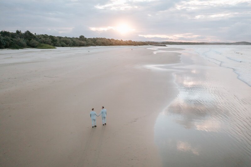 Arial shot of two men at their elopement walking along Noosa Main Beach
