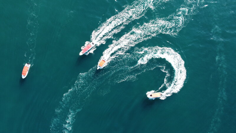 Two boats sailing next to each other on the water making waves