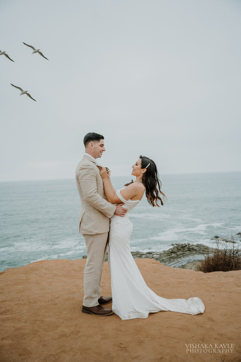 photo of bride and groom standing on the shore next to the ocean taken by Elopement photographer San Diego