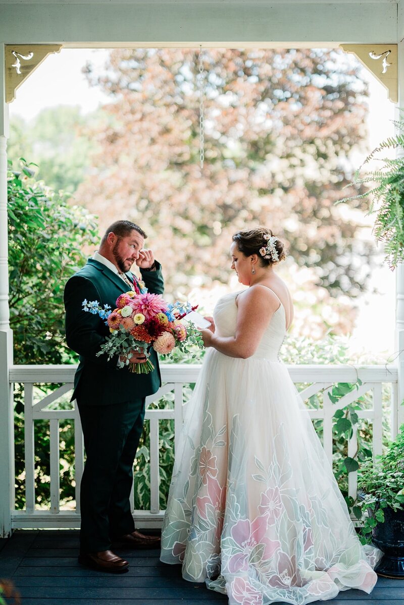 A groom wiping away his tears as he reads vows to his bride