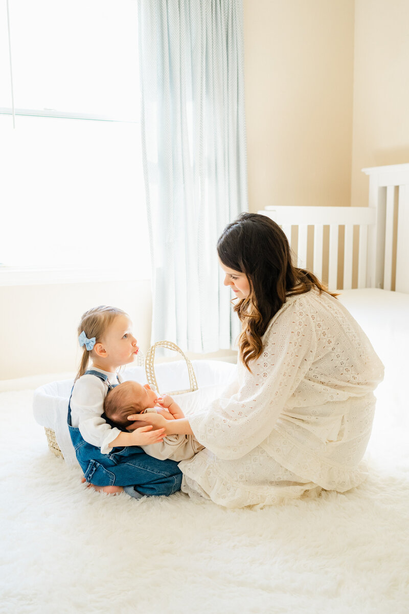 Austin, TX Faily & Newborn Photography | A mother sits in a nursery with her newborn baby and her toddler girl.