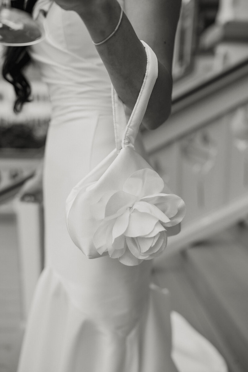 Black and white close up of a bride's floral styled satin purse.