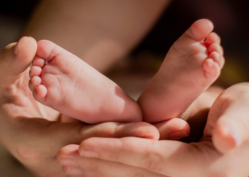 Newborn feet craddled in a father's loving hands