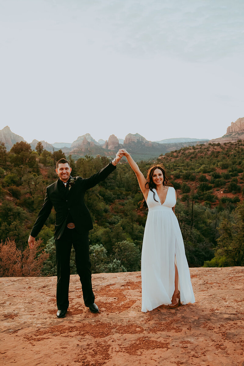 couple raising arms in excitement after wedding 