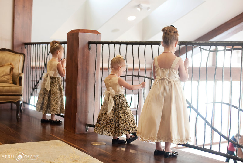 Flower girls look down at the wedding reception from the balcony at Cielo at Castle Pines wedding venue in Colorado