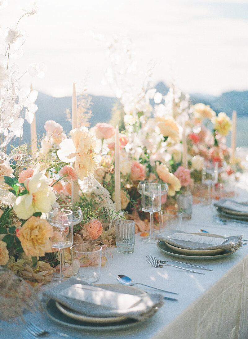 A Colorful Long and low floral centerpiece runner with peach, yellow and blush whimsical florals.