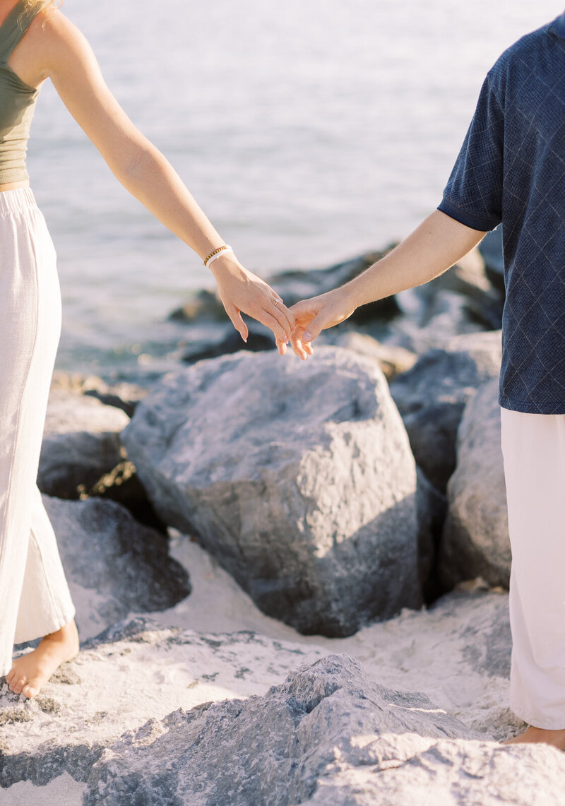 Couple holds hands for engagement on the beach