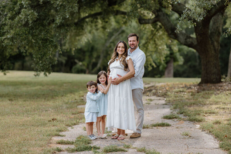 family dressed in light colored neutrals standing under large East Texas oak tree