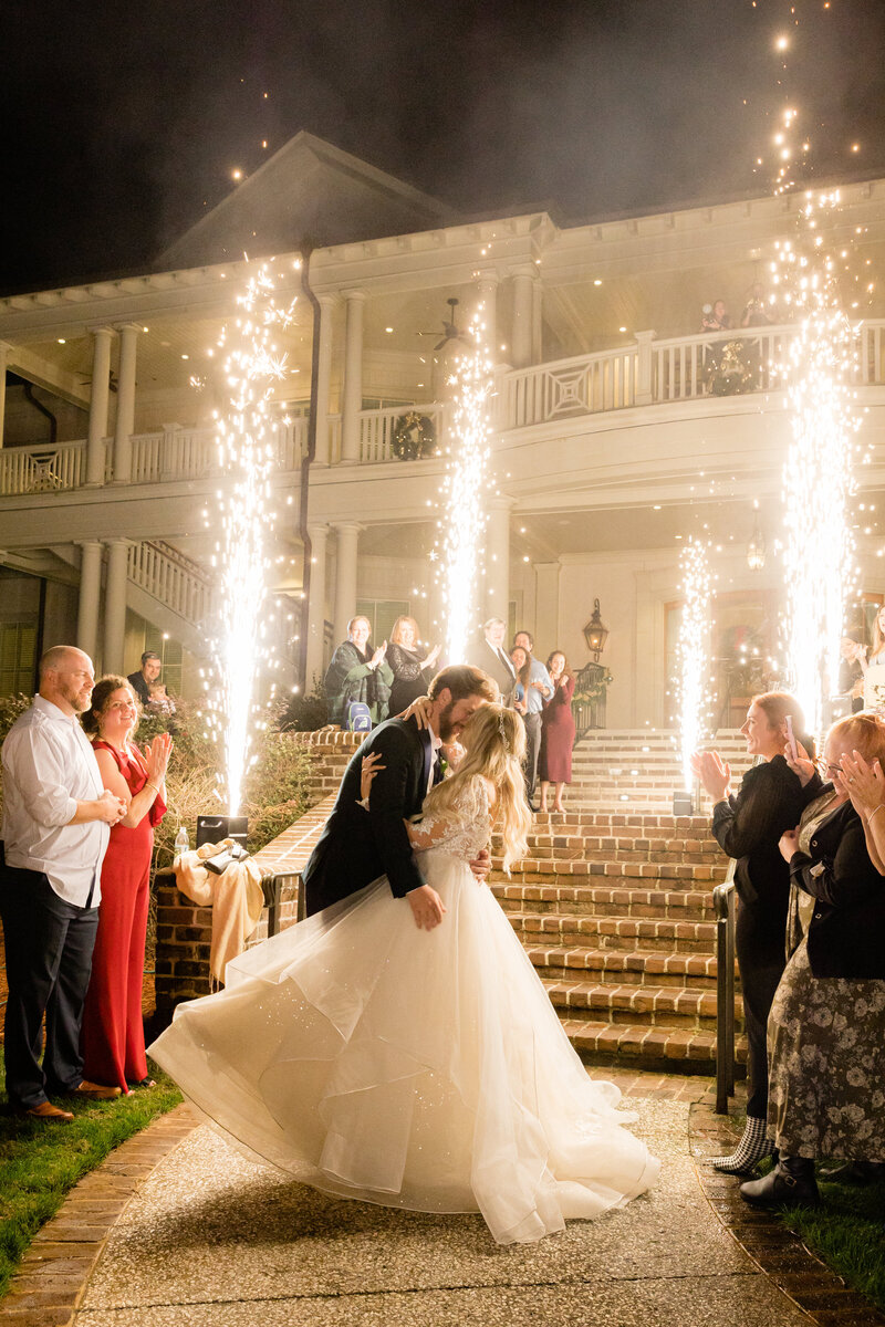 A newlywed couple shares a magical kiss during their grand sparkler exit at a luxury wedding in Sea Pines, Hilton Head. A breathtaking celebration with dazzling fireworks.