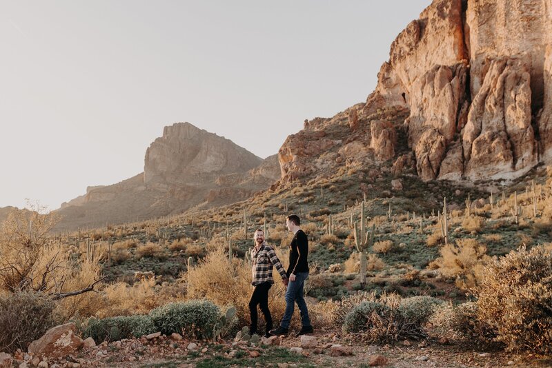 Couple walk through spacious desert for engagement photos