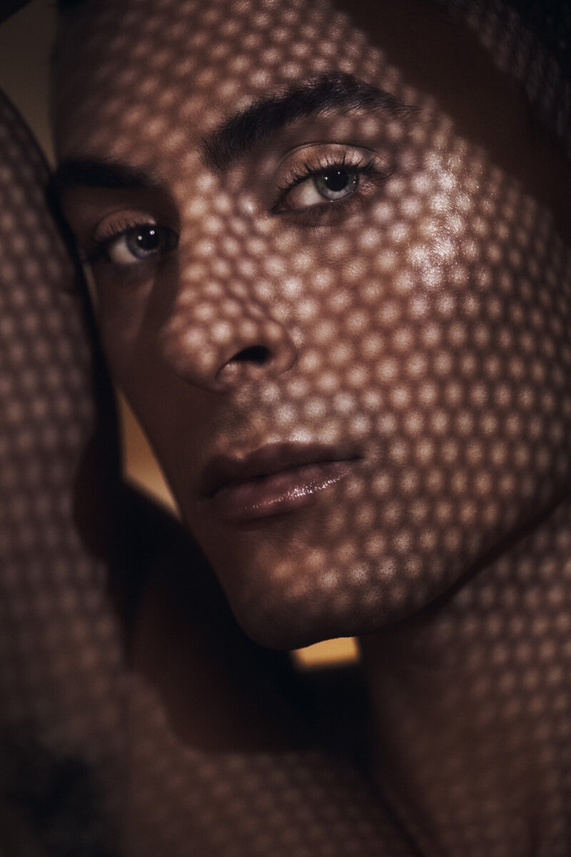 Studio shot of Cory with a hand covering part of his face, creating a dramatic effect, by Ylva Erevall.
