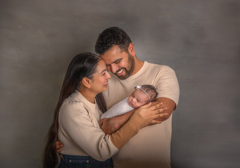 "Parents lovingly holding and looking at their newborn baby girl during a studio photography session in Ottawa"