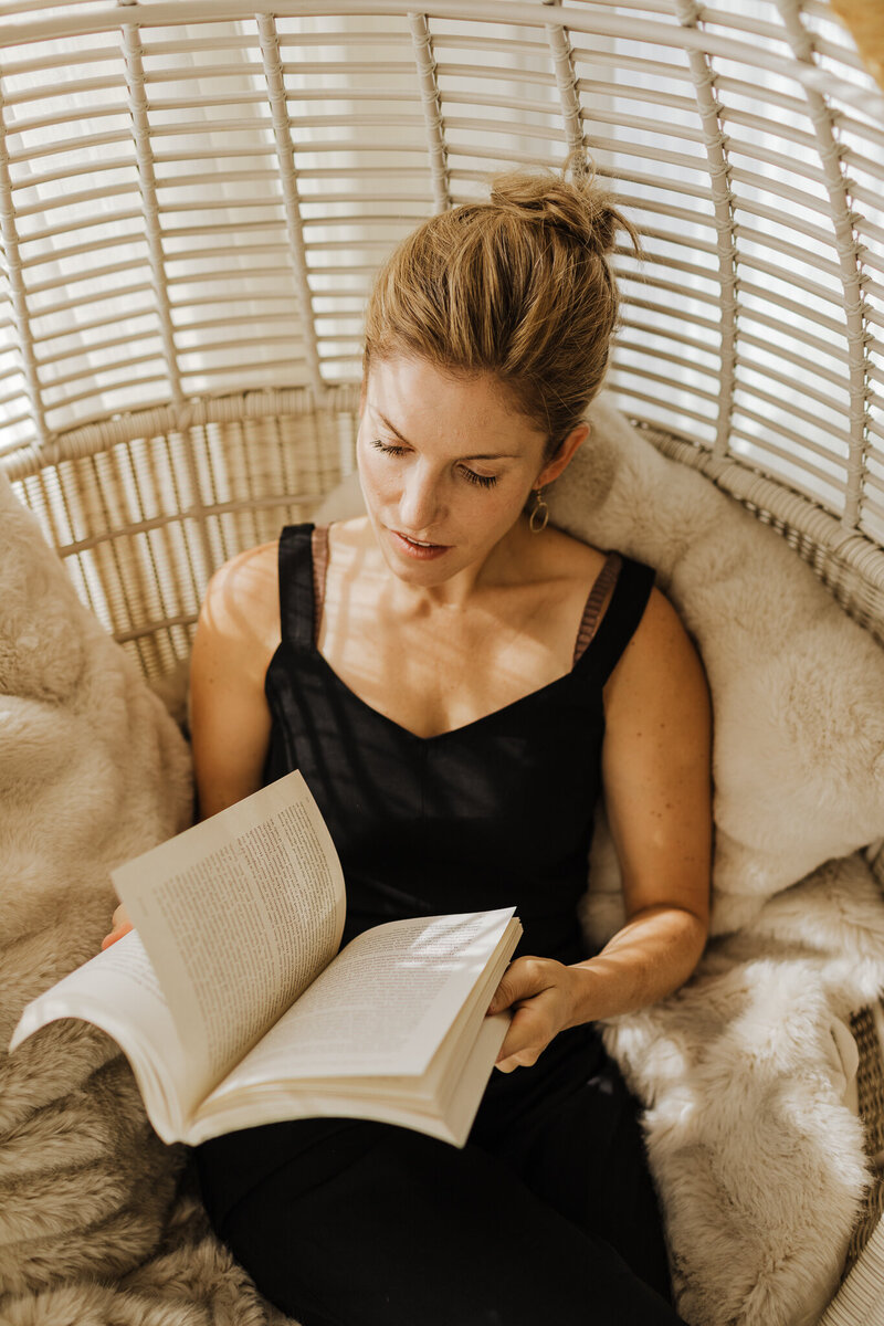 Lela Tuhtan flipping through a book while sitting in a chair.
