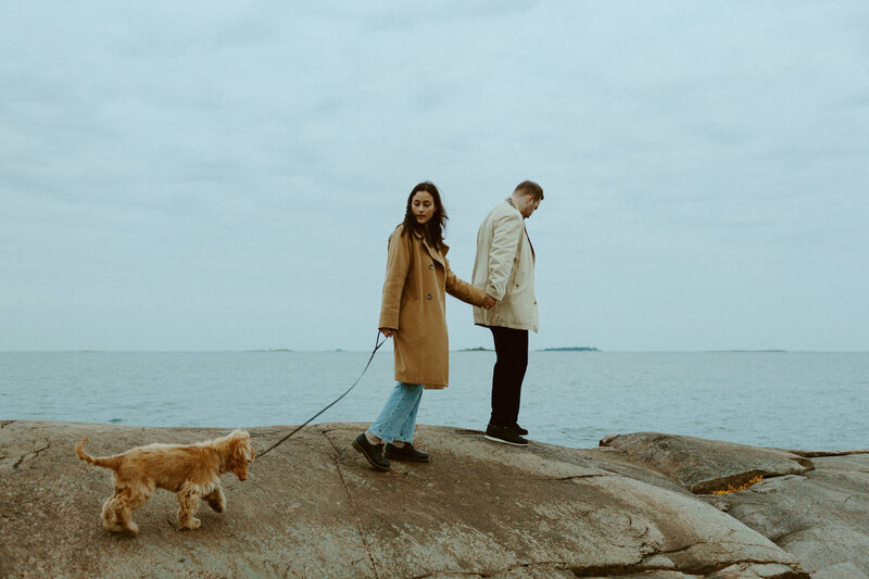 Pari kävelee rantakalliolla koiran kanssa syksyllä Lauttasaaressa Helsingissä