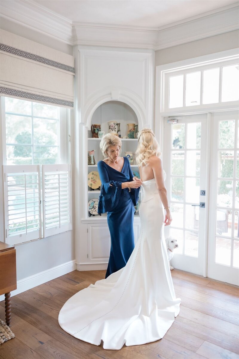 Bride getting dressed with her mom on her wedding day by Orlando wedding photographer 