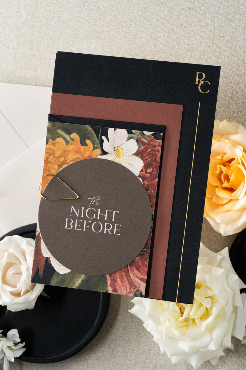 White curved menu card on a plate with a brown velvet napkin and flowers