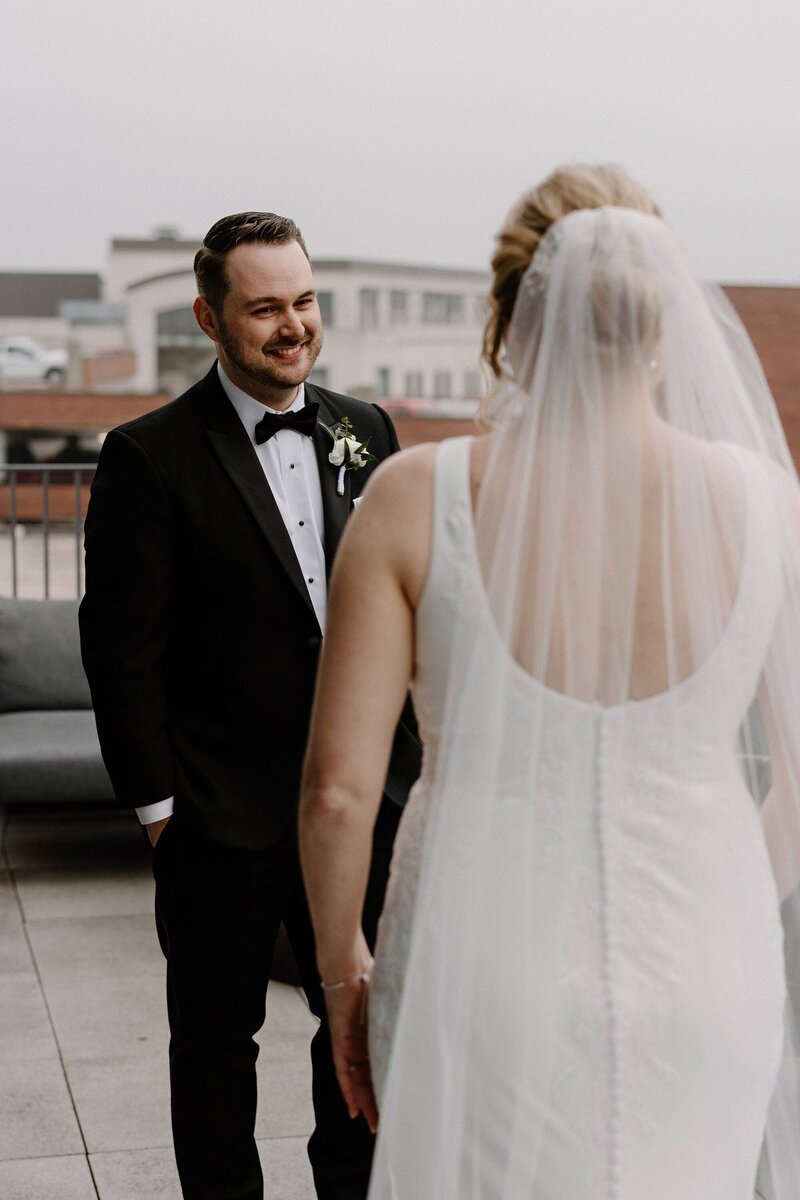 a groom smiling as he sees his bride for the first time