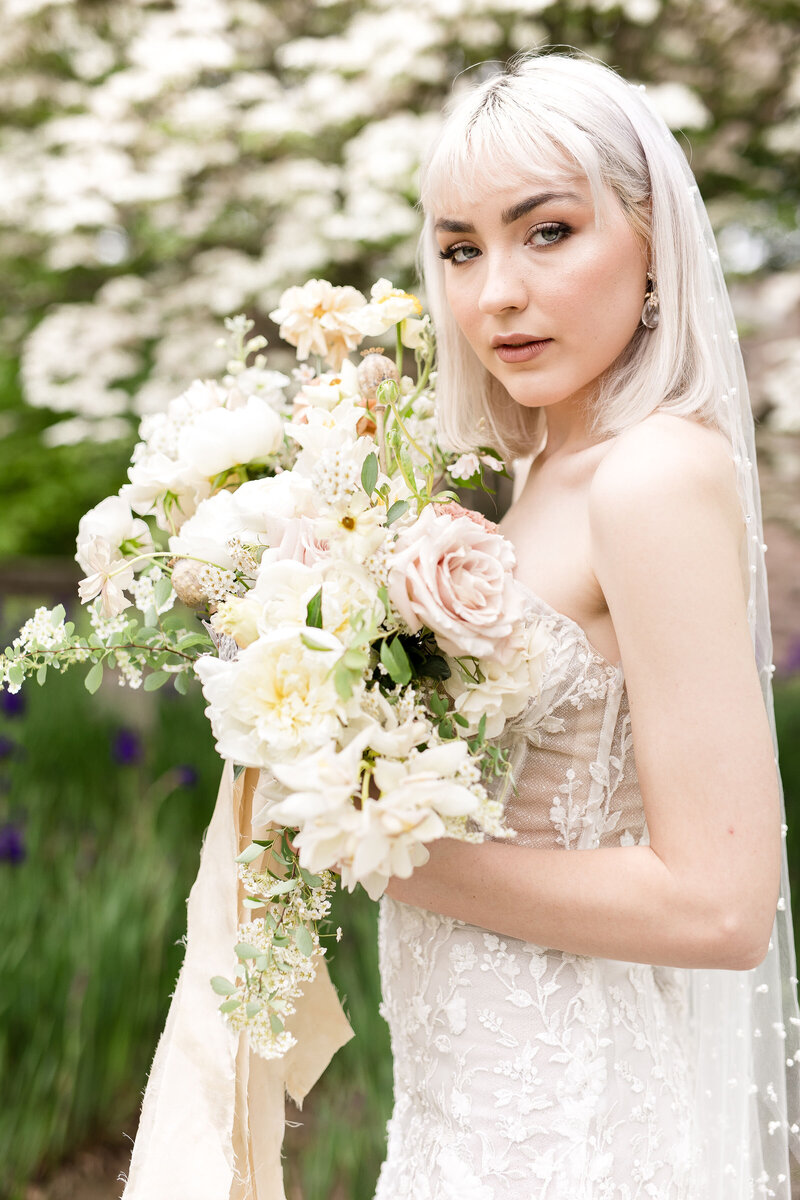 Bright image of a bride holding a flower bouquet outdoors