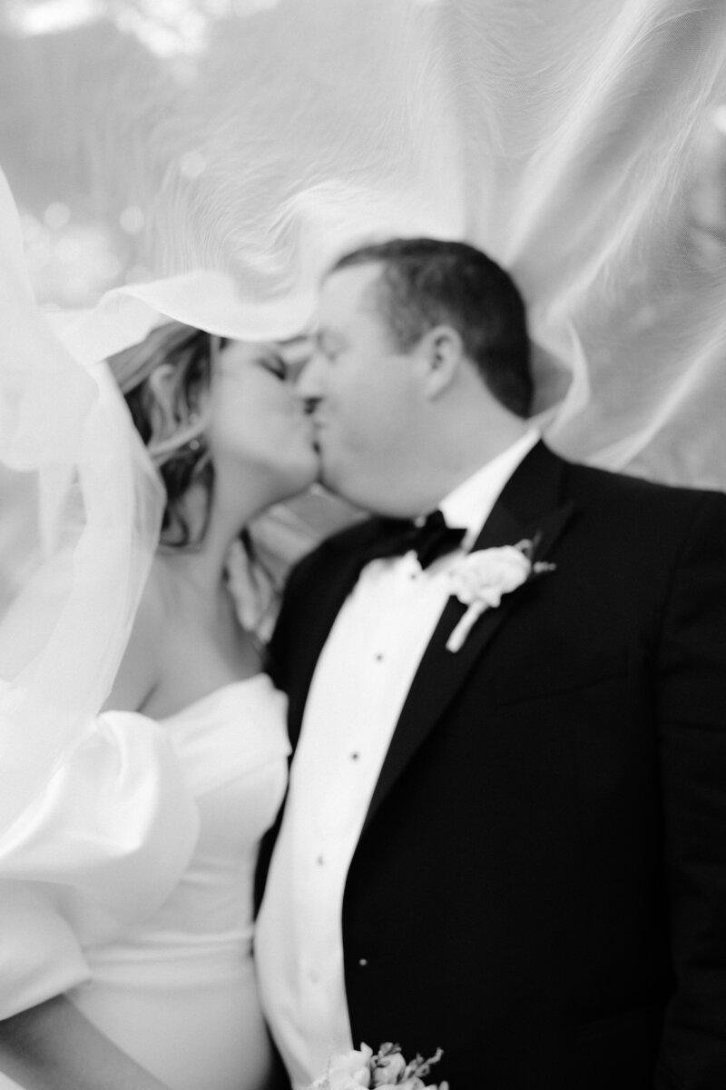 bride and groom kiss under veil