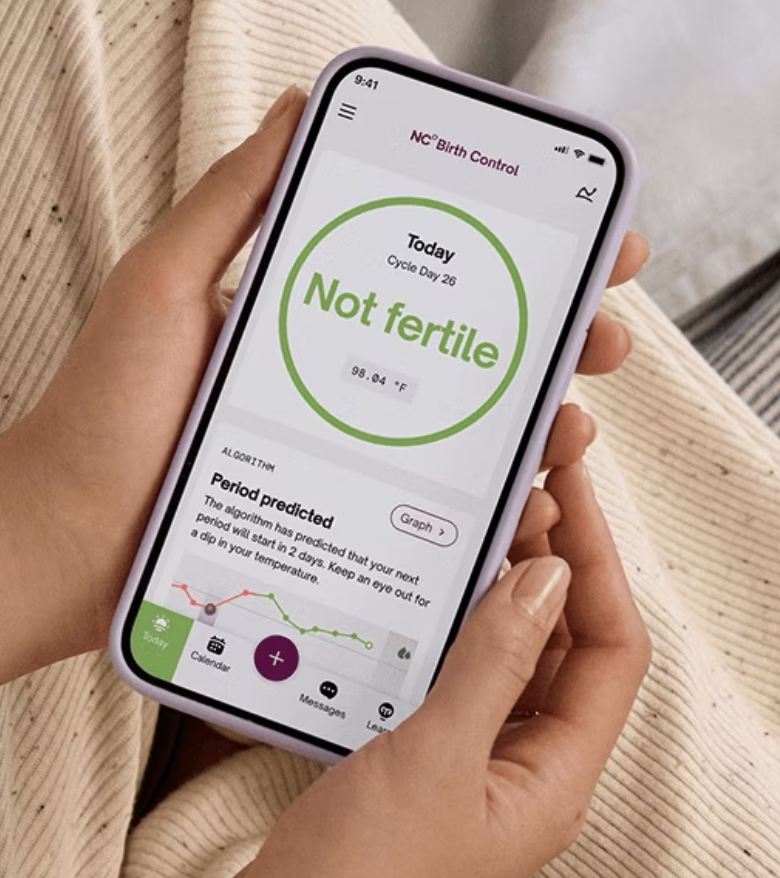 Hands holding a glass of water on top of a white table.