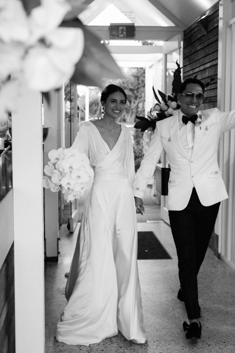 Newly married couple celebrating, bride wearing long silk wedding dress by sustainable British designer