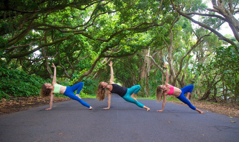 Three girls practice yoga in the road in Hawaii