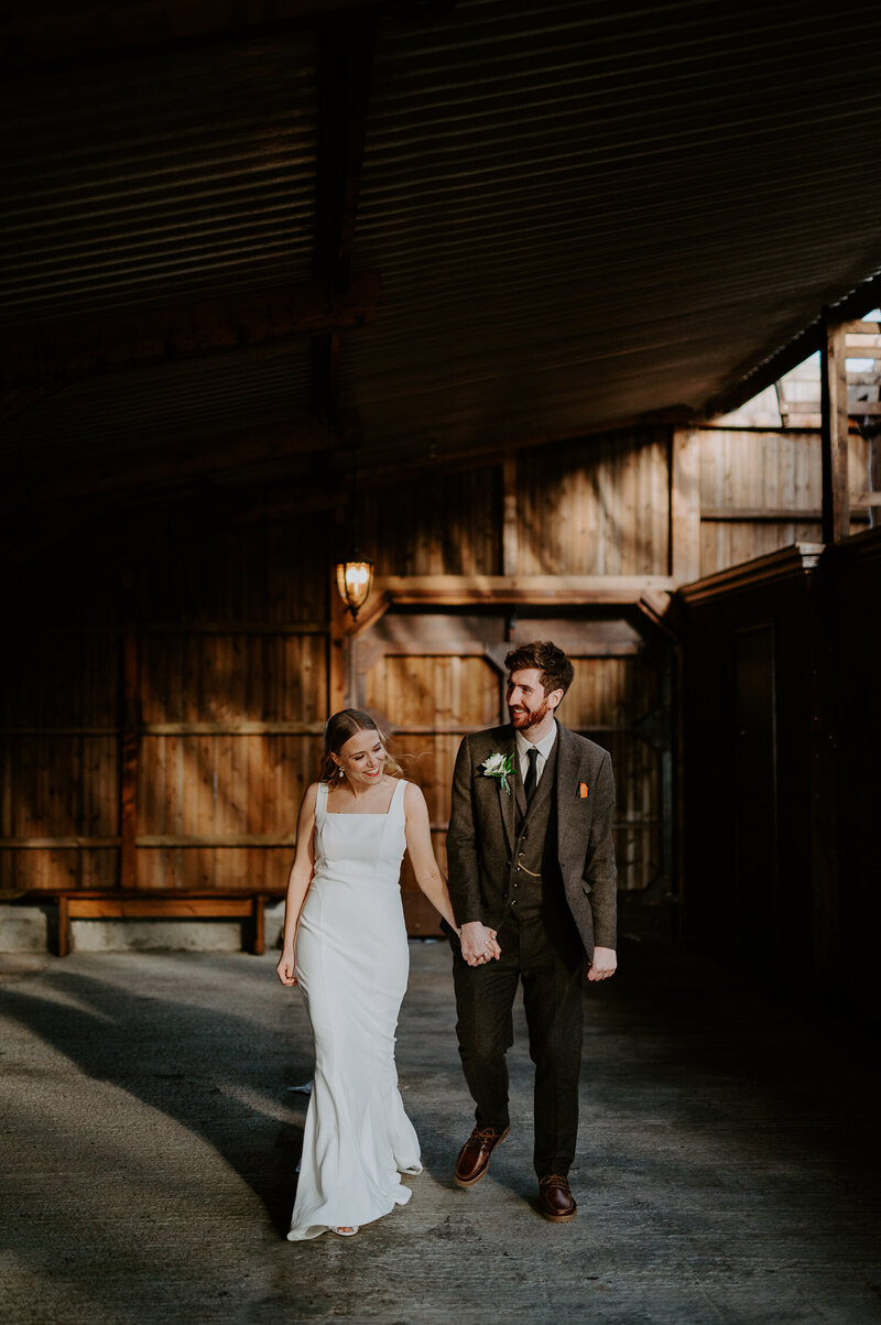 A couple walk in the stables barn at The Willow Marsh Farm wedding venue. 