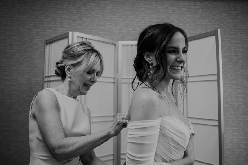 A person zipping up someone's wedding dress