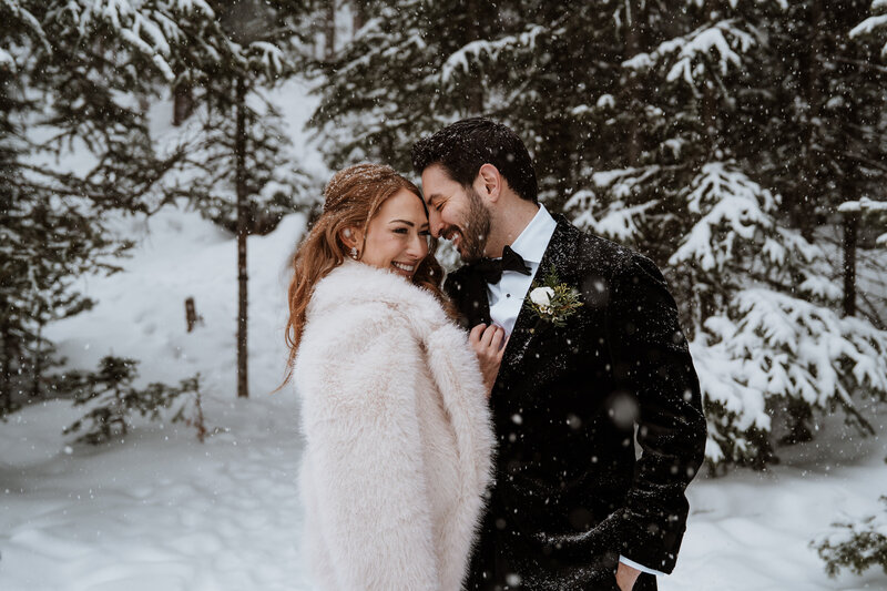 Bride and groom embrace in the snow, smiling during winter Breckenridge elopement photography session.