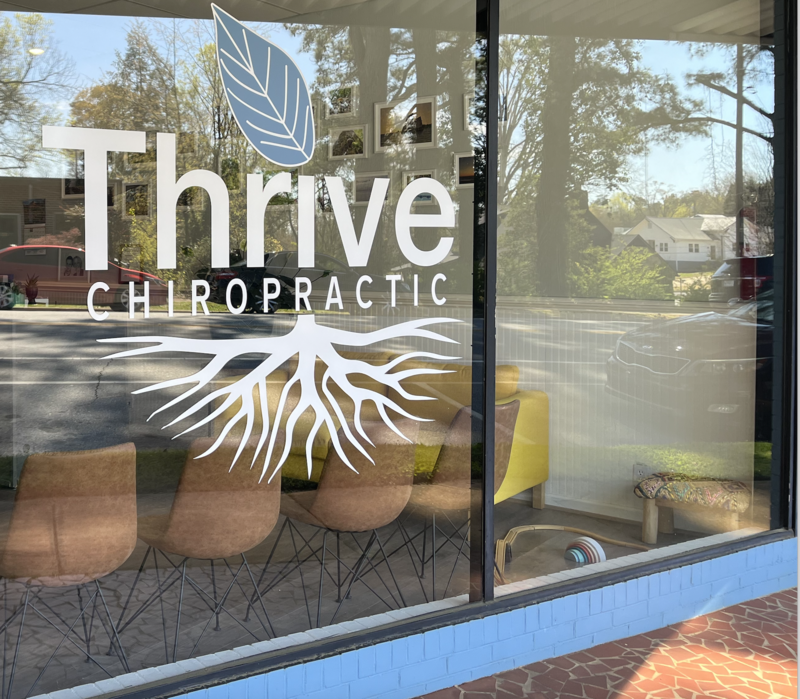 Thrive Chiropractic's logo grandly displayed in their large front window.