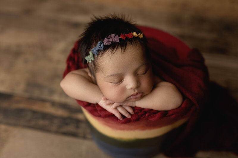 Rainbow baby in a rainbow coloured bucket with a rainbow headband