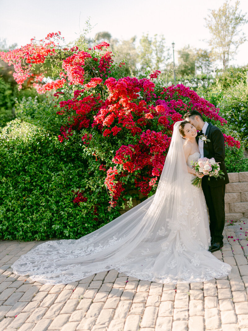 An unforgettable wedding moment surrounded by lush bougainvillea and golden light—captured with soft elegance by Los Angeles Top Destination Wedding Luxury Photographer Michael Asmussen. From Temecula Valley Wine Country to Tuscany, Italy this image embodies timeless beauty, couture bridal styling, and modern romance with a soulful lens.

在盛开的三角梅与金色阳光的映衬下，这是一幕令人难忘的婚礼瞬间——由洛杉矶顶级目的地婚礼摄影师 Michael Asmussen 柔和而优雅地捕捉。
从特曼库拉酒乡到意大利托斯卡纳，这幅影像融合了永恒美学、高定新娘造型与现代浪漫氛围，透过镜头娓娓道来一段充满灵魂的爱情故事。